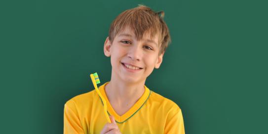 Junge im Fußballtrikot mit Zahnbürste