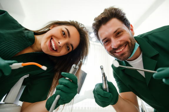 Zwei Zahnärzte beugen sich lächelnd über die Kamera